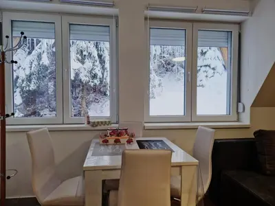 a dining room with a table and chairs and windows at Kod Strica in Kopaonik