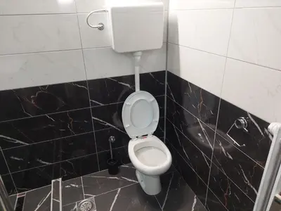 a bathroom with a white toilet in a black tiled wall at Rajna in Pirot