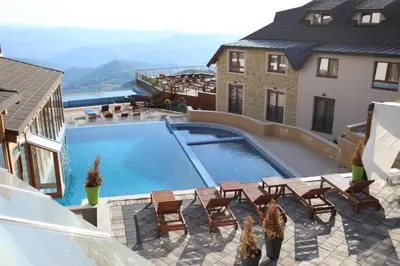 a large swimming pool with chairs and a house at Milmari resort Nlux21 in Kopaonik