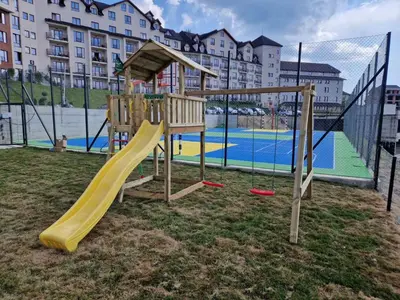 a playground with a yellow slide and a tennis court at Milmari resort Nlux21 in Kopaonik