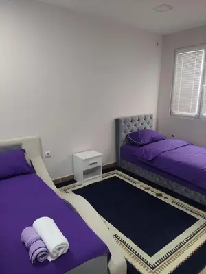 a bedroom with two beds with purple sheets and a rug at Comfort in Pirot