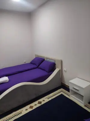 a bedroom with a bed with purple pillows and a table at Comfort in Pirot