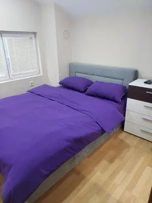 a bed with purple sheets in a white bedroom at ASTRA in Pirot