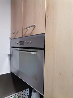 a kitchen with a stove and wooden cabinets at MDM Apartman Vrnjačka Banja in Vrnjačka Banja