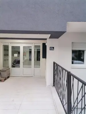 a front porch of a white building with glass doors at MDM Apartman Vrnjačka Banja in Vrnjačka Banja