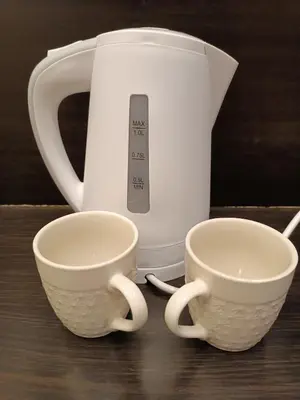 two white cups sitting next to a tea kettle at M Central Park in Niš