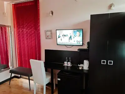 a room with a desk and a television on a wall at M Central Park in Niš