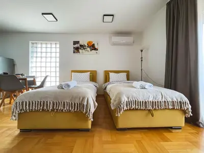 two beds in a room with a table and a dining room at Apartmani TEO in Prokuplje