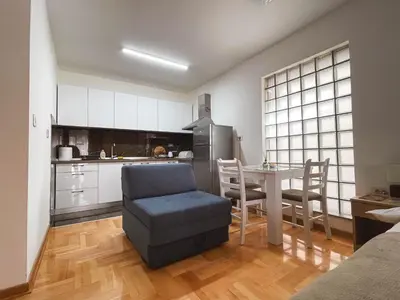 a kitchen with a table and a chair and a refrigerator at Apartmani TEO in Prokuplje