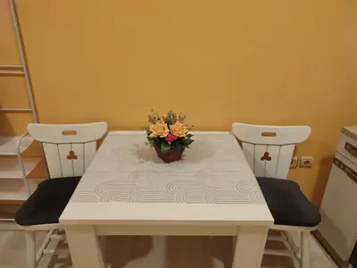 a table with two chairs and a vase of flowers on it at Soba Lara in Kruševac