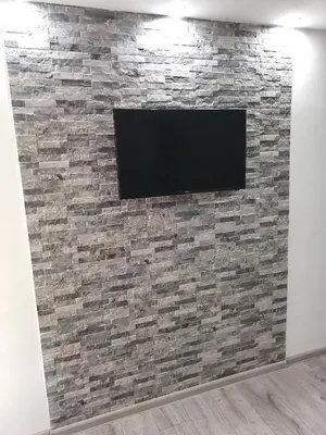 a flat screen tv on a stone wall at Apartman Mata in Soko Banja