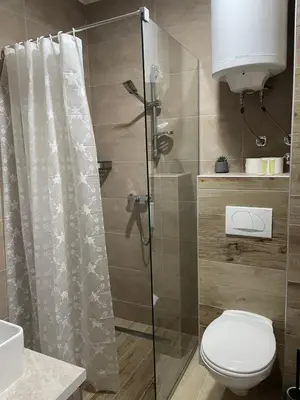 a bathroom with a toilet and a glass shower at Apartmani NLUX and SPA in Kopaonik