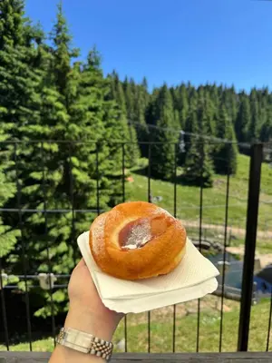 a person holding a donut on a napkin at Apartmani NLUX and SPA in Kopaonik