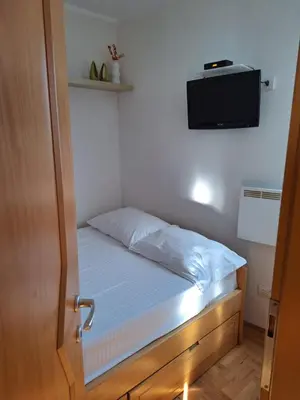 a small bedroom with a bed with a tv on the wall at Kraljevi čardaci Čar 3 in Kopaonik