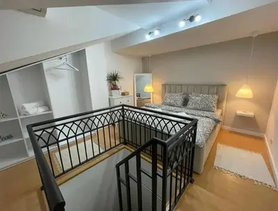 a bedroom with a bed and a staircase in a room at Apartman Element in Kruševac