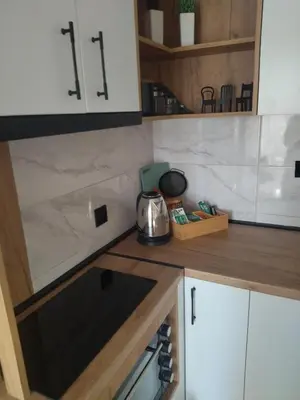 a kitchen with white cabinets and a stove top oven at Apartman Element in Kruševac