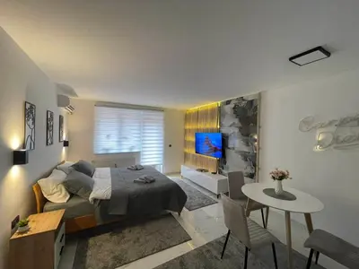 a bedroom with a bed and a table and a tv at Apartman Afrodita Lux 1 in Niš
