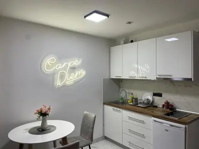 a kitchen with a table and a sign that reads cape drop at Apartman Afrodita Lux 1 in Niš
