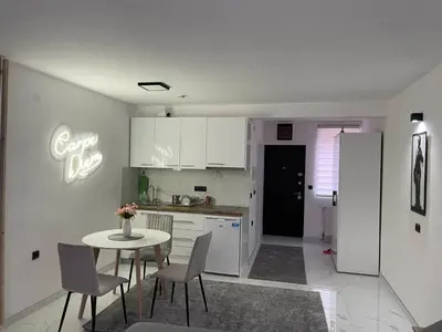 a kitchen with a table and chairs and a kitchen with white cabinets at Apartman Afrodita Lux 1 in Niš