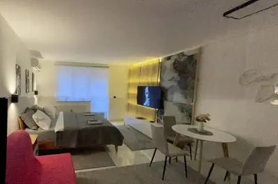 a living room with a bed and a table and chairs at Apartman Afrodita Lux 1 in Niš