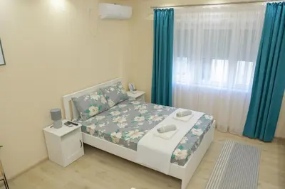 a bedroom with a bed and a window with blue curtains at Vila Harmony in Pirot