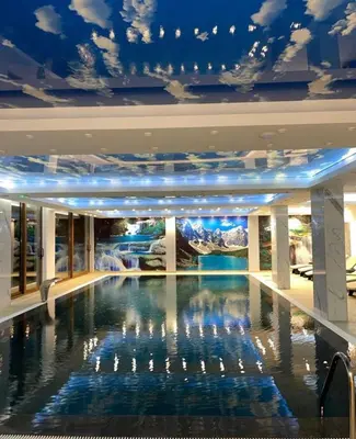 a swimming pool in a hotel with a ceiling with clouds at President Kop Apartman A843 in Kopaonik