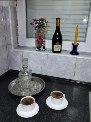 two cups of coffee on a counter with a bottle of wine at Apartman Raj in Vrnjačka Banja