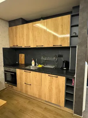 a kitchen with wooden cabinets and a black counter top at Suncana Planina Glory-Kop in Kopaonik