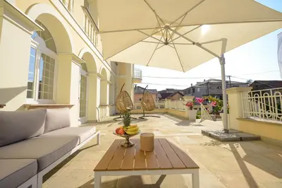 a patio with a couch and a table with an umbrella at Vila Palas in Vrnjačka Banja
