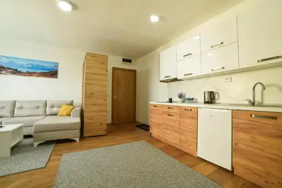 a kitchen and living room with a couch and a table at Apartman La Foresta Kopaonik in Kopaonik