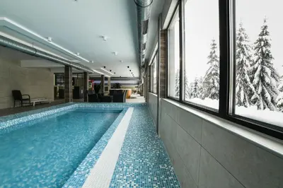 a swimming pool in a building with windows at Apartman La Foresta Kopaonik in Kopaonik