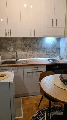 a kitchen with white cabinets and a table and a tableablish at MS Apartman in Vrnjačka Banja