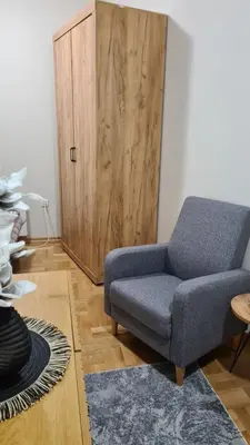 a living room with a blue chair and a wooden door at MS Apartman in Vrnjačka Banja