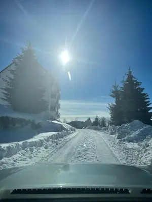 a snow covered road with the sun in the sky at Gencian resort in Kopaonik