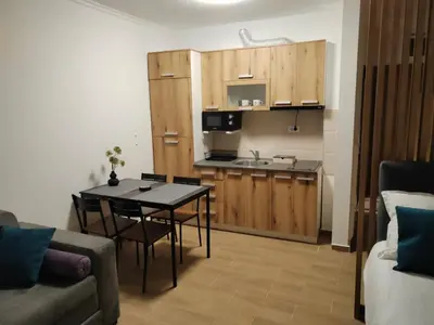 a living room with a table and a kitchen at Apartman BM403 in Kopaonik