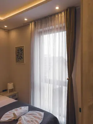 a bedroom with a bed and a window with curtains at Milmari Premier - Daisy Apartments in Kopaonik