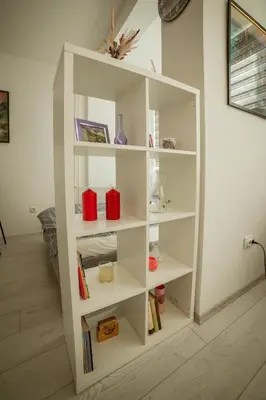 a white book shelf in a room with books at Quince in Bor