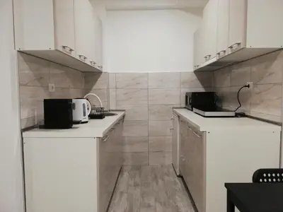 a kitchen with white cabinets and a tile wall at Quince in Bor
