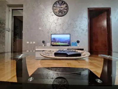 a living room with a tv and a clock on the wall at Victory apartment in Niš