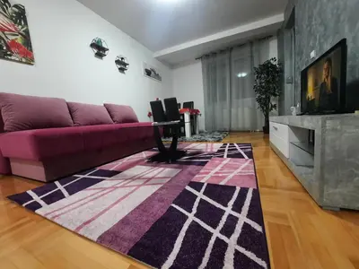 a living room with a purple couch and a rug at Victory apartment in Niš