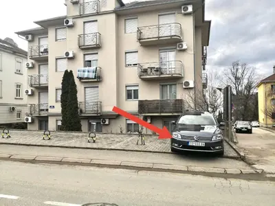a car parked in front of a building with a red arrow at Apartman Danica in Vrnjačka Banja