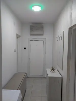 a white room with a door with a bench and a table at Apartman Aleksić u centru grada in Knjazevac.