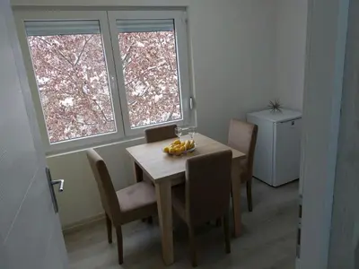 a dining room with a table and chairs and two windows at Apartman Aleksić u centru grada in Knjazevac.