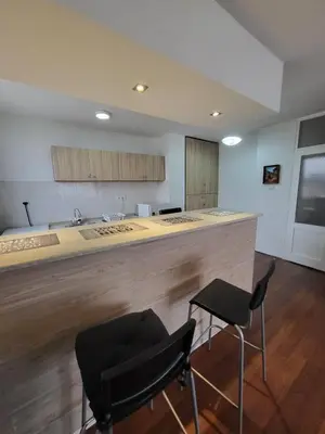 a kitchen with a counter with two chairs and a bar at Apartman Nina in Niš