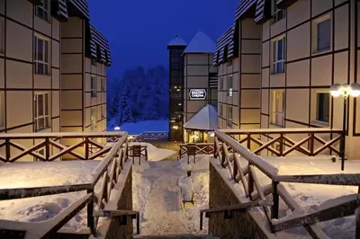 a snow covered courtyard of a building at night at Apartman Čardaka 11/42 in Kopaonik