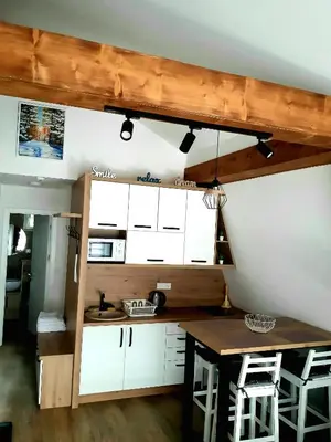 a kitchen with white cabinets and a table with stools at White Eagle Kopaonik - Beli Orao in Kopaonik