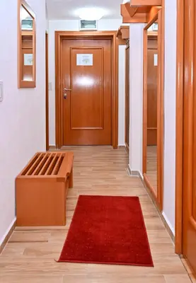 a hallway with a door and a red rug at Apartman Sakovic in Kopaonik