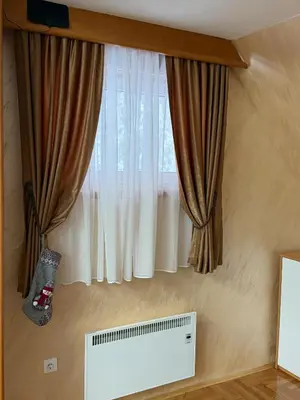 a window with curtains and a air conditioner under it at Apartman Sakovic in Kopaonik
