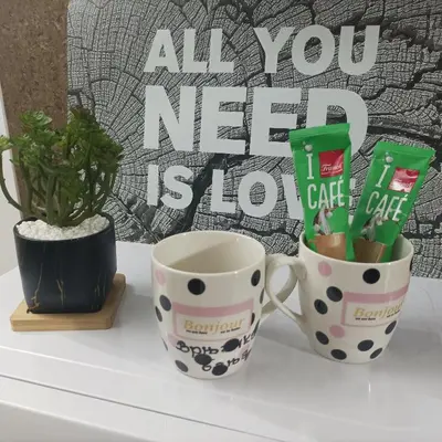two coffee mugs on a table with a sign that reads all you need stop at Apartman Vrnjacka zora in Vrnjačka Banja