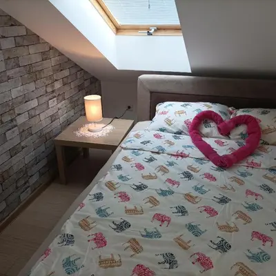 a bed with a heart pillow on it next to a table at Apartman Vrnjacka zora in Vrnjačka Banja